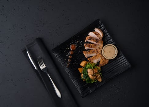 a dish of chicken on the black wooden surface, top view