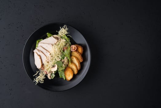 a dish of chicken on the black wooden surface, top view