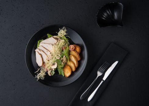 a dish of chicken on the black wooden surface, top view