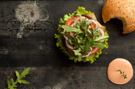 cheeseburger on an old wooden surface of dark color. hamburger with sauce and ketchup on an old wooden surface of dark color