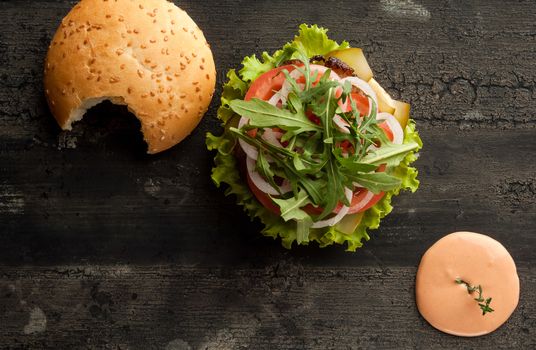 cheeseburger on an old wooden surface of dark color. hamburger with sauce and ketchup on an old wooden surface of dark color