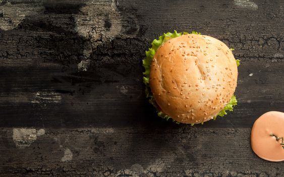 cheeseburger on an old wooden surface of dark color. hamburger with sauce and ketchup on an old wooden surface of dark color