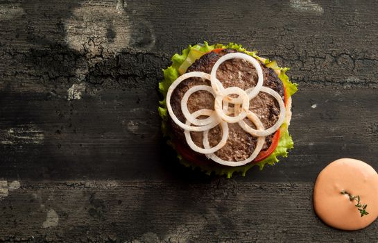 cheeseburger on an old wooden surface of dark color. hamburger with sauce and ketchup on an old wooden surface of dark color