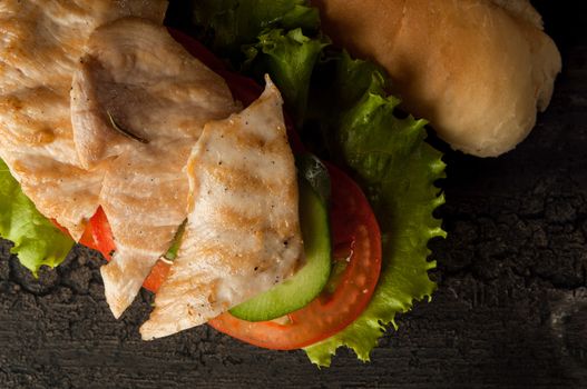 cheeseburger on an old wooden surface of dark color. hamburger with chicken meat on an old wooden surface of dark color