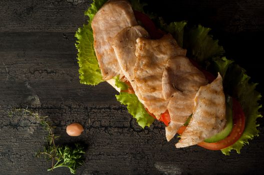 cheeseburger on an old wooden surface of dark color. hamburger with chicken meat on an old wooden surface of dark color