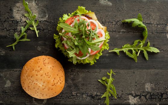 cheeseburger on an old wooden surface of dark color. hamburger with meat and tomato on an old wooden surface of dark color