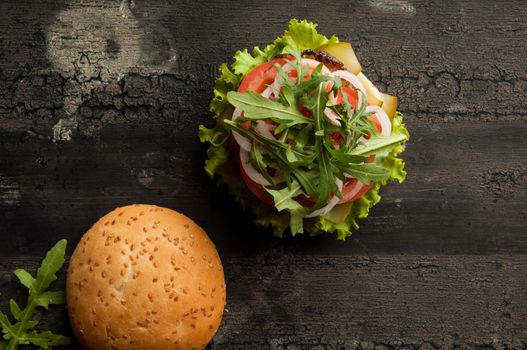 cheeseburger on an old wooden surface of dark color. hamburger with meat and tomato on an old wooden surface of dark color