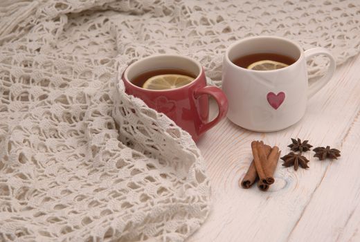 two cups of tea with lemon and scarf on wooden boards