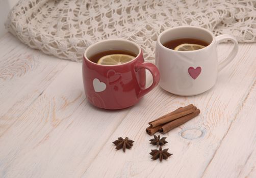 two cups of tea with lemon and scarf on wooden boards