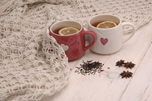 two cups of tea with lemon and scarf on wooden boards
