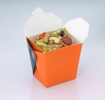 chinese food to takeaway. noodles with meat and vegetables in a cardboard box on a light background