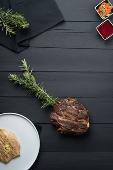 fried meat with greens, sauce and gravy on a black wooden background