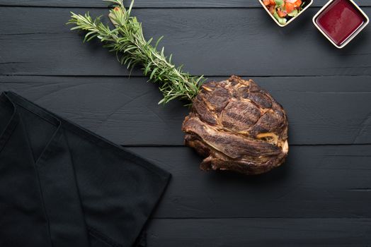 fried meat with greens, sauce and gravy on a black wooden background