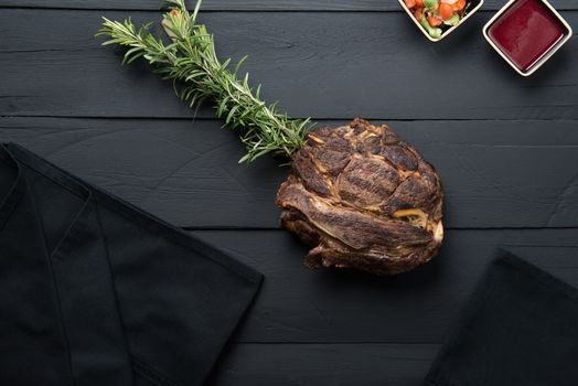 fried meat with greens, sauce and gravy on a black wooden background