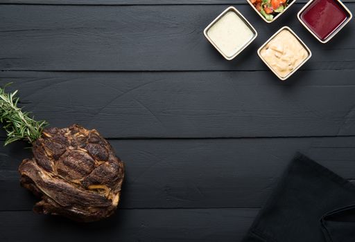 fried meat with greens, sauce and gravy on a black wooden background