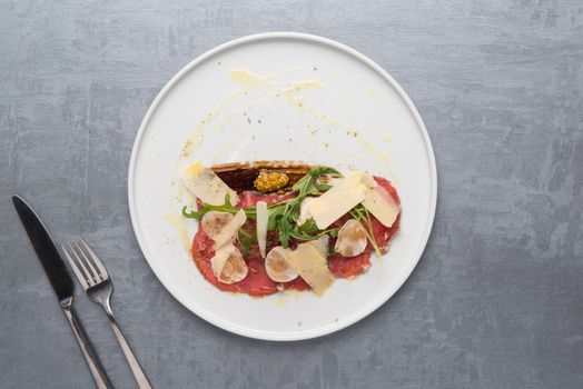 cheese and meat with greens in a plate on a gray background