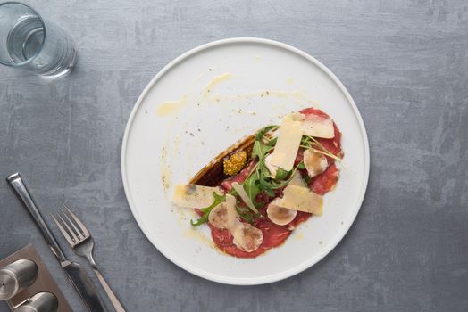 cheese and meat with greens in a plate on a gray background