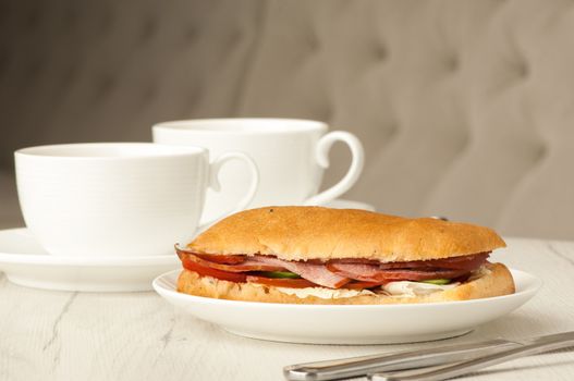 sandwich and two cups of coffee on a table with cutlery