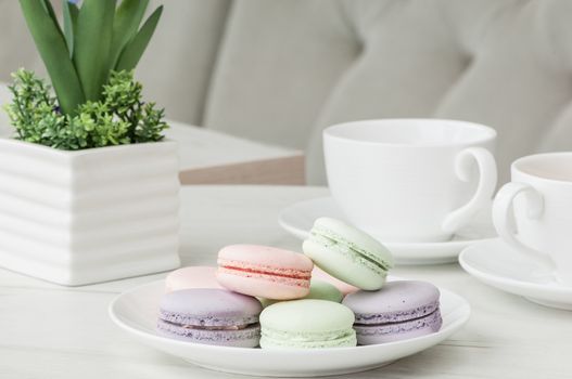 Round cookies on a plate and two cups on a table with flowers