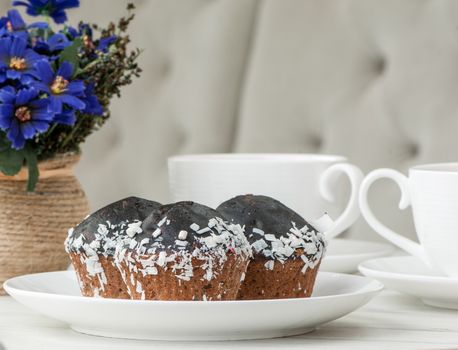 cake on a plate and two cups of tea on the table with flowers and a fork