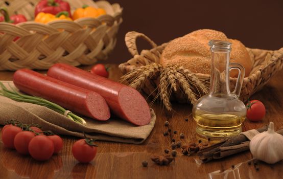 sausage and bread in a wicker basket and vegetables and garlic on a table