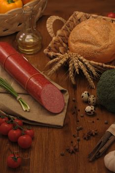 sausage and bread in a wicker basket and vegetables and garlic on a table