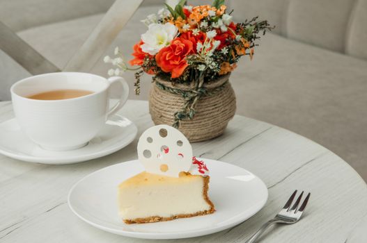 cake on a plate and a cup of coffee and fork on a table with flowers