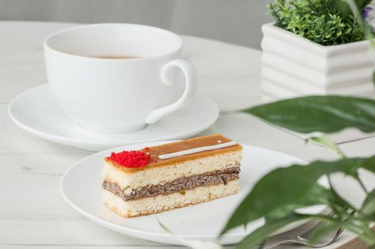 cake on a plate and a cup of coffee on a table with flowers