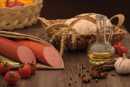 sausage and bread in a wicker basket and vegetables and garlic on a table