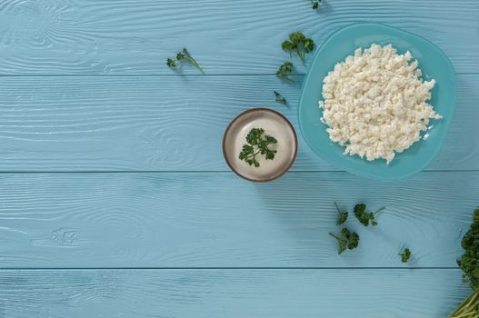 Cottage cheese in a plate and yogurt on a wooden blue background, top view. healthy eating concept