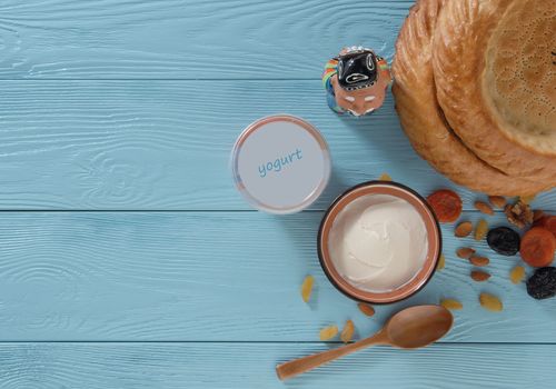 yogurt in a plastic package with a flat cake on a blue wooden background, top view. healthy eating concept