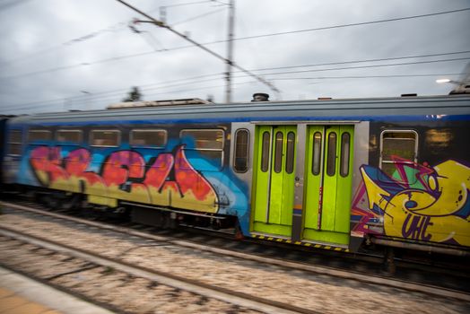 teni,italy may 28 2020 :trains panning at the station at speed with people inside and colored by graffiti