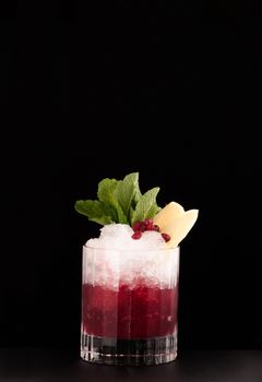 one glass cup with pomegranate drink and ice on a dark background