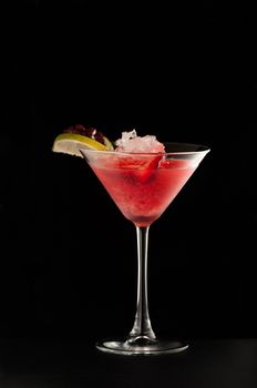 one glass beaker with a drink pomegranate and citrus on a dark background