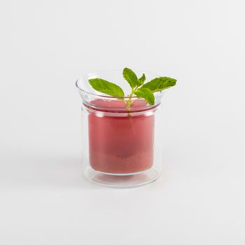 a glass of tea fruit drink and a leaf of mint on white background, isolated