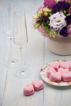 pink cookies in the shape of hearts on a plate and glasses of champagne with flowers on wooden boards on Valentine's Day