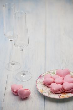 pink cookies in the shape of hearts on a plate and champagne glasses on wooden boards on Valentine's Day