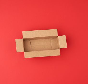 open empty square brown cardboard box for transportation and packaging of goods on red  background, top view.