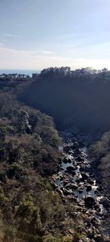 A divine ray of light in a valley with brook filled with rocks surrounded by green bushes in Jeju Island, South Korea