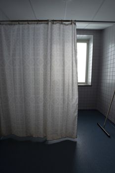 Bathroom with old shower curtain in hospital.
