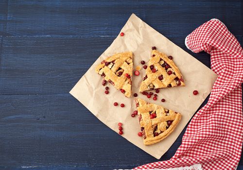 triangular slices of baked cranberry pie on brown paper, top view