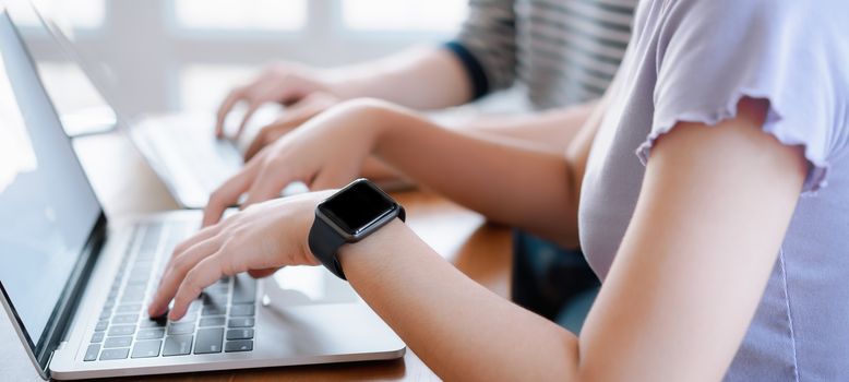 Cropped shot of young couple typing on computer during working day in home office. Working at home concept