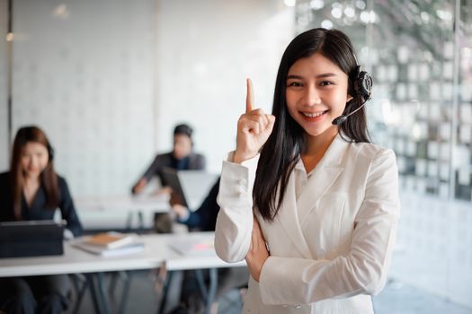 Confident female customer services agent with headset working in a call center office. Customer service team support concept