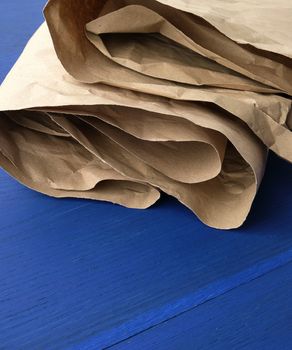folded brown crumpled kraft paper sheet on blue wooden background, close up