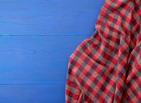 red checkered fabric on a blue wooden background, abstract background, place for an inscription