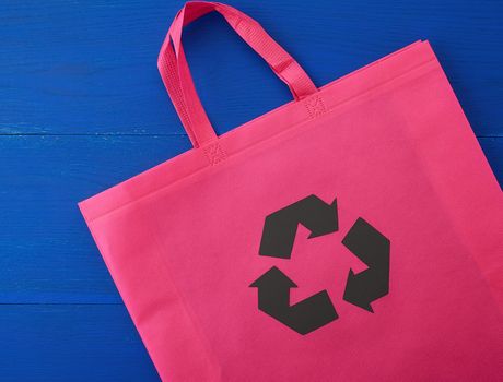 Reusable pink viscose bag on blue wooden background, plastic waste reduction concept