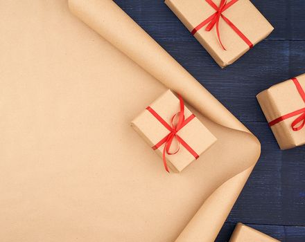 brown kraft paper, packed gift boxes and tied with a red ribbon, red heart, set of items for making gifts. Gift wrapping. Package design, copy space