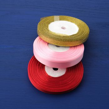 twisted red, pink, golden silk ribbons on a blue background, element for the designer, close up