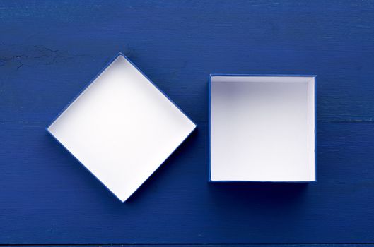 open empty square cardboard box for gifts on a blue wooden background, top view