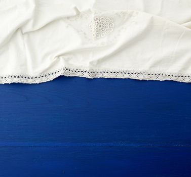 white kitchen textile towel folded on a blue wooden table from old boards, top view, empty space. Decoration element.